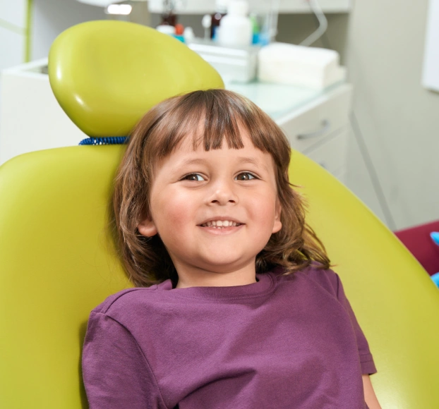 Child patient smiling in yellow dental chair at airway consultation appointment in Aurora, IL.