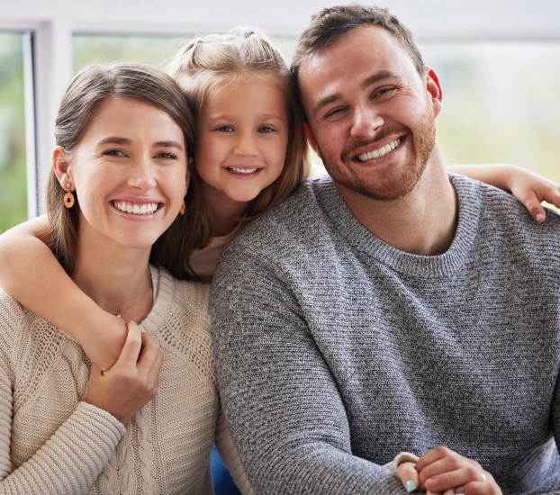 Happy family with young daughter smiling at dental office in Aurora, IL.