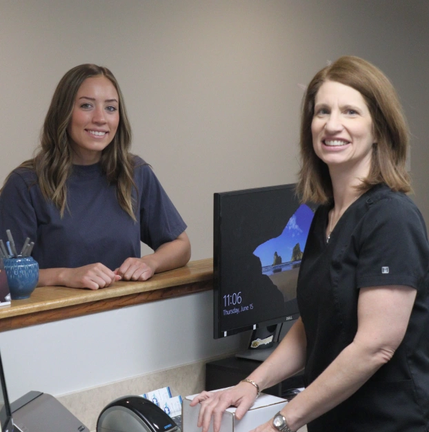 Dental team members at reception desk discussing membership plans at Aurora, IL dental office.