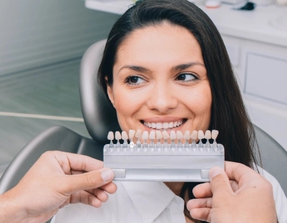 Patient displaying dental veneer shade guide at Aurora dental office for cosmetic smile planning.