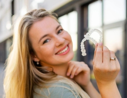 Young woman smiling with clear aligners at dental office in Aurora, IL.