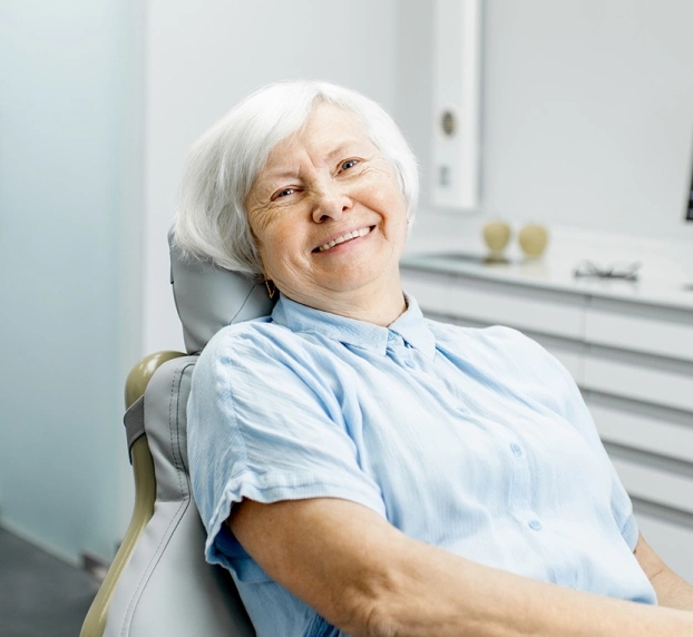 Senior patient smiling in dental chair at Aurora dental office on Prairie Street receiving root canal therapy.